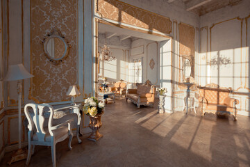 rich apartment interior with golden baroque decorations on the walls and luxury furniture. the room is flooded with the rays of the setting sun