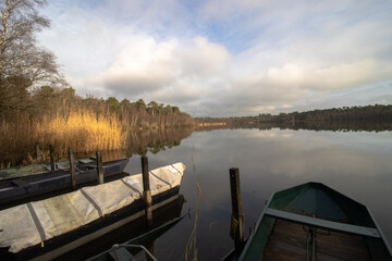 Naklejka premium Fishermen boats in a lake during autumn time. Clouds reflecting on water.