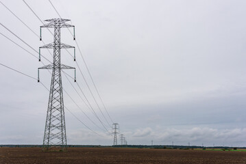 Extra-high voltage 400 kV overhead power line on large pylons, used for long distance, very high power transmission. Cloudy sky and copy space - 411026145