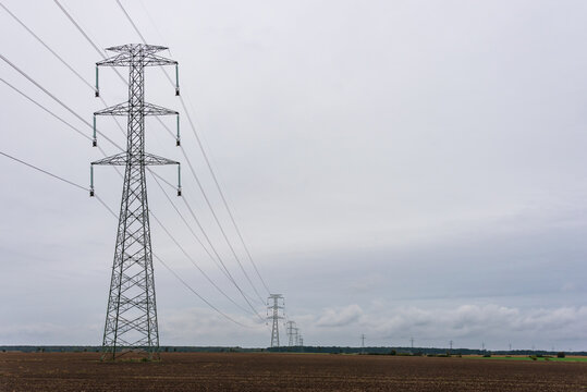 Extra-high voltage 400 kV overhead power line on large pylons, used for long distance, very high power transmission. Cloudy sky and copy space