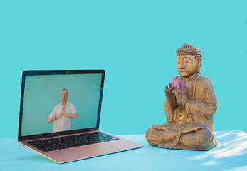 View of a laptop and a buddha. Meditation instructor giving online yoga classes via video call on a laptop.