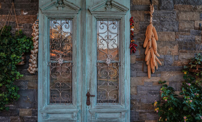 old blue door with hanging vegetables and flowers on the wall