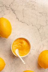 Homemade tangy lemon curd decorated with fresh fruit on marble background.Top view. Copy space for...