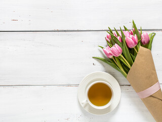 Pink tulips and cup of tea on white wooden table. Copyspace, top view