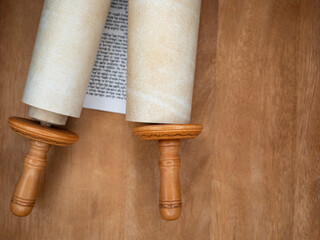 A fragment of the Torah scrolls on a brown wooden table..copy space - obrazy, fototapety, plakaty