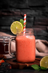 Pink Strawberry lime healthy smoothie with honey on wooden board and dark background