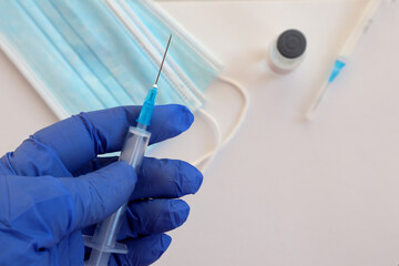 A syringe in the hand in a glove close-up against the background of medicines
