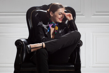 fashion caucasian business style woman in black suit laughing, sitting in chair