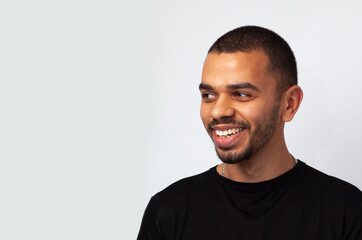 young attractive blackskin man smiling looking aside in black sweathshot isolated, side copy space