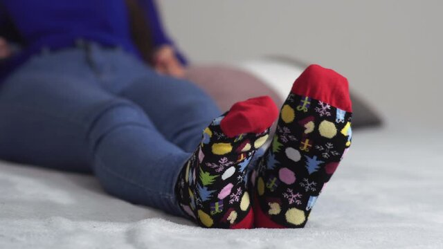 Female foot in warm colorful christmas wool sock ,Woman sleeping and relaxing in bed concept. Warm and cozy white socks in the bed