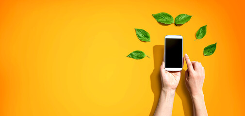 Person holding a smartphone with green leaves