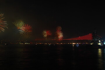 Fireworks over Istanbul Bosphorus during Turkish Republic Day celebrations. Bosphorus Bridge with red lighting and lasers at night time.