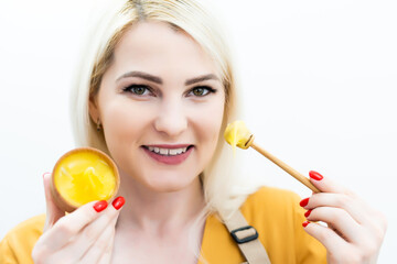 Happy young woman holding wooden bowl of honey, copy space