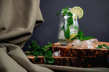 Mojito cocktail on a dark background. Wooden stand.