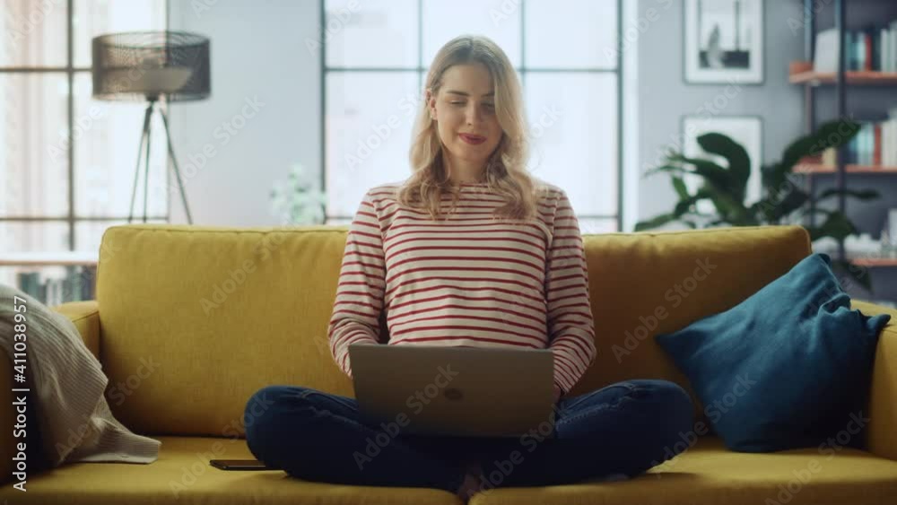 Poster beautiful female specialist making a video call on laptop computer at home living room while sitting