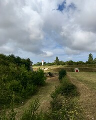 Fototapeta na wymiar landscape with field and lighthouse against cloudy sky