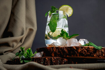 Mojito cocktail on a dark background. Wooden stand. Ice and mint.
