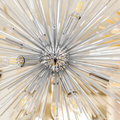 Close-up of a switched off incandescent lamp in a ceiling with a clear glass chandelier in the form of a modern style tube. The concept of decor for the interior. Indoors. Square photo size.