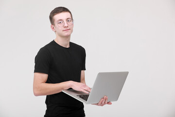 Distance learning online education. portrait of a young man in a black T-shirt with glasses with a laptop on a white background. copy space