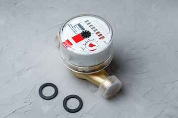 New hot water meter with two rubber gaskets on a gray concrete background.