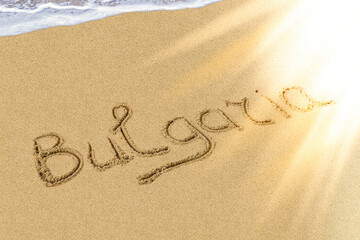 Bulgaria title on the light sand beach near the black sea coast. Brilliant sun ray falls on the letters.