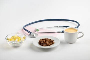 Grains of coffee on a plate, pills, stethoscope. High blood pressure concept.