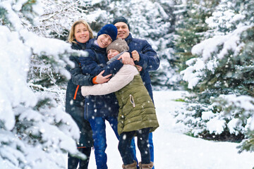Obraz premium family portrait in the winter forest, parent and children, beautiful nature with bright snowy fir trees