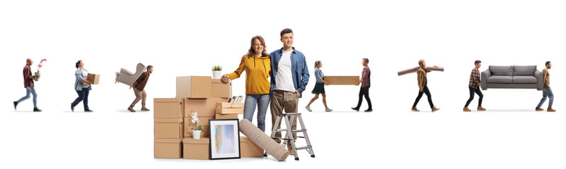 Young couple posing with packed cardboard boxes and other people carrying household items