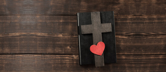 Cross. Open Bible. Bible book on a wooden table. Love god. Wooden cross of Jesus. Red heart. The...