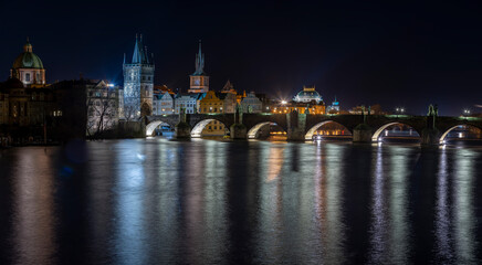 Fototapeta na wymiar .illuminated Charles Bridge on the Vltava River and light from street lighting is reflected on the surface in the center of Prague at night