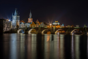 Fototapeta na wymiar .illuminated Charles Bridge on the Vltava River and light from street lighting is reflected on the surface in the center of Prague at night