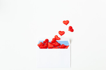 A white mailing envelope with flying out red decorative hearts is located on a white background at the bottom of the image. Valentine's Day theme. Free space for text.
