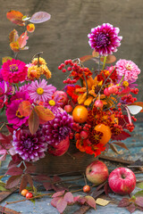 Beautiful autumn pink red orange bouquet with dahlia, fall flowers, colorful leaves and apples	