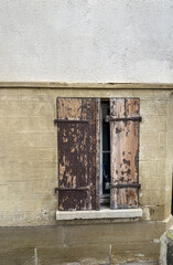 Fassade mit Fenster, alten braunen, verwitterten  Holzfensterlädnen bis auf Spalte verschlossen, Fenstersims Metallscharniere, Straßenschild