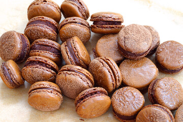 Homemade Chocolate macaron cookies with cocoa dusted on top and ganache filling

