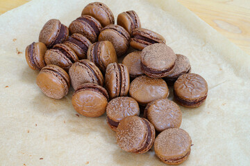 Homemade Chocolate macaron cookies with cocoa dusted on top and ganache filling
