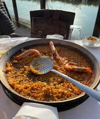Appetizing paella in a big pan served in waterside restaurant in El Palmar, Spain