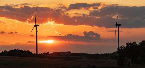 wind turbines during sunset under partly cloudy skies