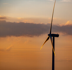 wind turbine during sunset under partly cloudy skies