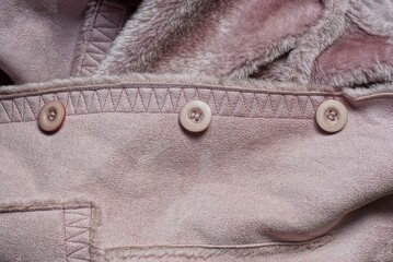 three plastic buttons on a brown suede winter jacket with fur