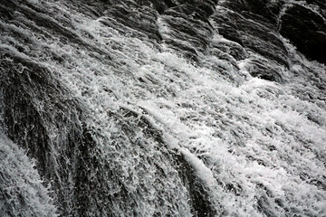 大波のあとの岩場を流れ落ちる海水