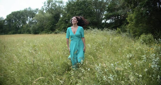  A girl in a long dress runs across a green meadow 