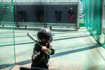 野球少年がバッティングセンターでバッティングしている写真