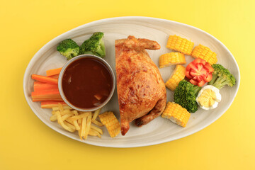 Half Ayam Kodok is Stuffed Whole Chicken with Meat and Egg, Serve with French Fries, Broccoli, and Carrots also Barbeque Sauce. Isolated on Yellow Background
