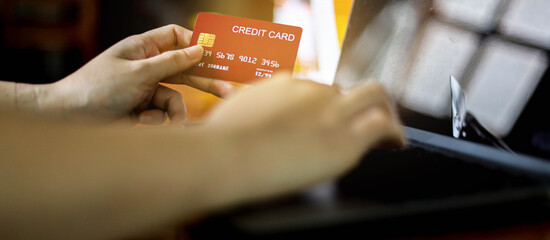 The person holds a red credit card and is filling out their credit card information to pay for goods online, credit cards can pay for goods and services both in the storefront and online shopping.