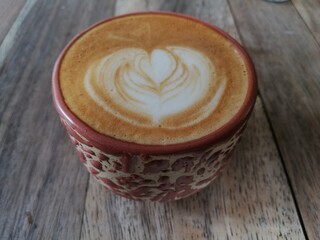 a cup of cappuccino with latte art on wood table. top angle view 