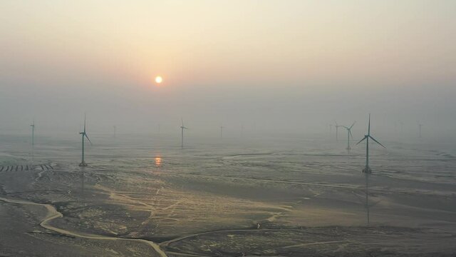 aerial view of wind farm in sunrise, sustainable energy on mud flats by drones shoot