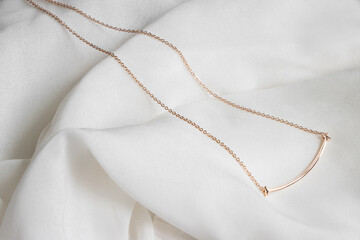 Closeup of a golden necklace with a shiny curvy line shaped pendant