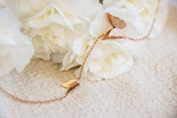 Closeup of a golden necklace with two butterflies pendant sitting on white carnations