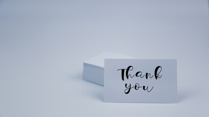 A word Thank You on white paper name card  with white background. Concept for presentation